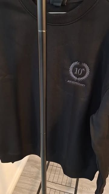 A 10th anniversary crest embroidered on a black crewneck
